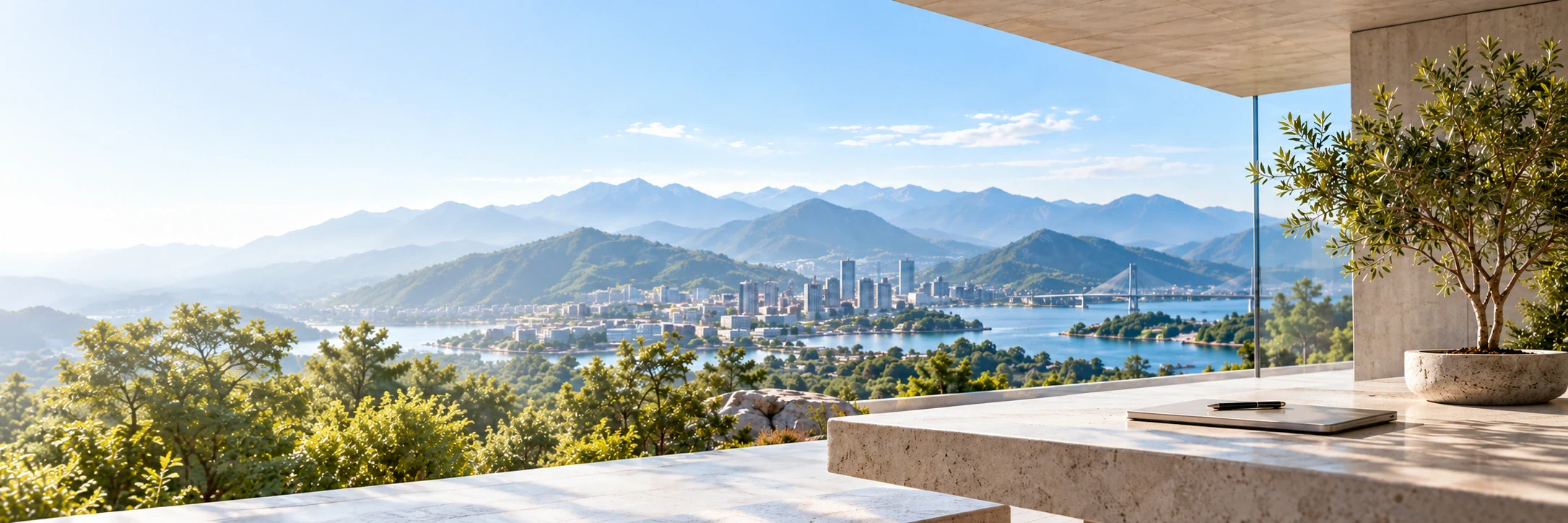 Empty stone terrace with a notebook overlooking a waterfront city and mountains.